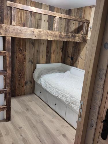 Ce lit se trouve dans un dortoir doté de murs en bois. dans l'établissement Appartement chaleureux 2 chambres 4-6 pers, à Montgenèvre