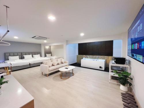 a living room with white furniture and a tv at The Space Hotel Lampang in Lampang