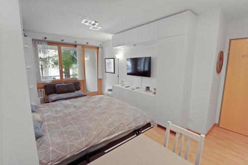 una camera con letto e TV a parete di Studio chaleureux avec vue sur les montagnes a Leukerbad