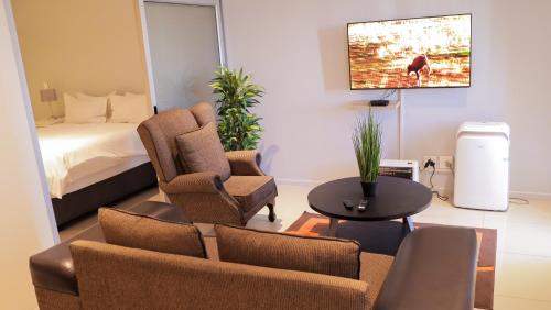 a living room with a couch and chairs and a bed at City Apartments at Freedom Plaza in Windhoek