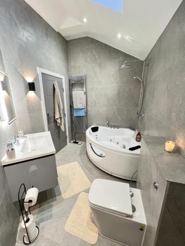 y baño con bañera, aseo y lavamanos. en Cozy Luxury Private Cottage en Greenford