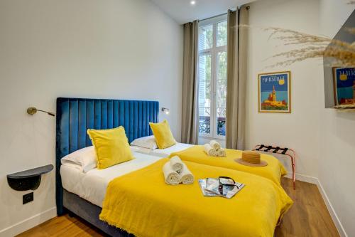 a bedroom with two beds with yellow sheets at Boutique Hôtel Provencia in Marseille