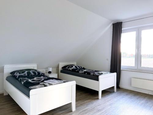 two beds in a white room with a window at Schöne Apartments I private Parkplätze I home2share in Münster