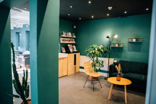 uma sala de estar com paredes verdes e uma mesa e cadeiras em Hostel by Hyve Basel em Basileia