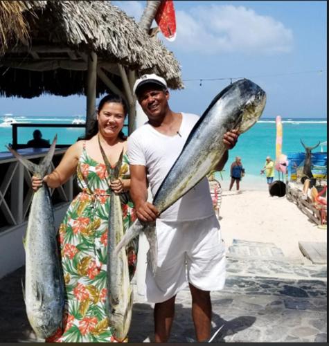 a man and a woman holding two large fish at Dios es Fiel - Ali Hotel in Punta Cana