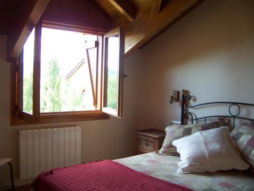 1 dormitorio con 1 cama y ventana grande en Apartamentos Chuandervera en Laspaúles