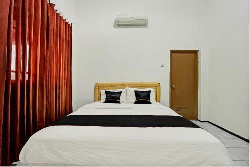 a bedroom with a large bed with two pillows at Capital O 1362 Ciliwung Guest House Syariah in Malang
