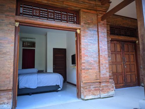 ein Schlafzimmer mit einem Bett und einer offenen Tür in der Unterkunft K'Ajeng Cottage in Penebel
