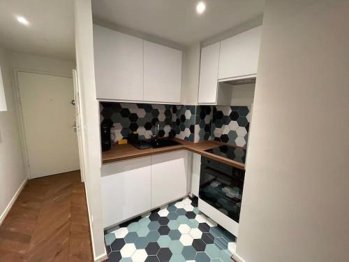 une cuisine avec des placards blancs et un sol en damier noir et blanc dans l'établissement La Lanterne - Magnifique T2 Strasbourg - Cathédrale à 300m, à Strasbourg