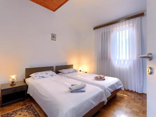 a bedroom with two beds with white sheets and a window at Apartment Josip in Crveni Vrh