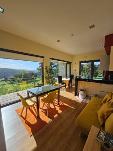 a living room with a glass table and yellow chairs at Junção - Apartamentos Completos in Miranda do Douro