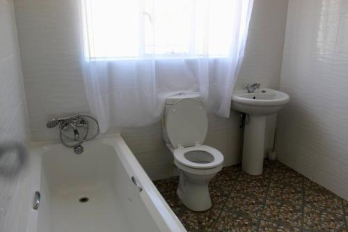 a white bathroom with a toilet and a sink at Lovely 4 bed in Mutare - 2178 in Umtali