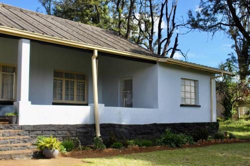 Umtali的住宿－Lovely 4 bed in Mutare - 2178，白色房子,有灰色的屋顶