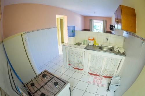 a small kitchen with a sink and a refrigerator at Pousada Flats Recanto Sonhos do Porto in Porto De Galinhas