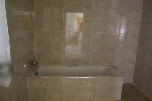 a bath tub in a bathroom with a tile wall at 2 bedroomed house with a lovely garden - 2177 in Umtali
