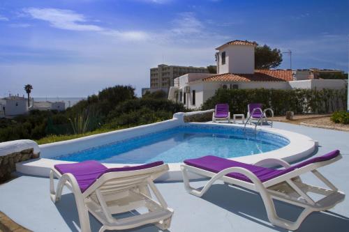 een zwembad met 2 ligstoelen en een zwembad bij Apartamentos Blue Beach Menorca in Cala en Blanes