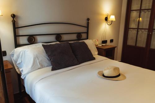 a hat sitting on top of a white bed at San Sebastián DOT Rooms in San Sebastián