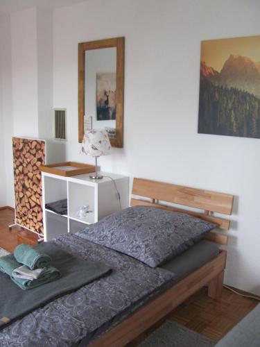 Schlafzimmer mit einem Bett und einem Wandspiegel in der Unterkunft #1Gemütliches ruhiges sonniges Balkonzimmer mit Gemeinschaftsbad W-Lan Airport nah Late Night Check in in Trunkelsberg