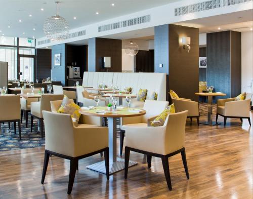 un restaurant avec des tables et des chaises dans un bâtiment dans l'établissement DoubleTree by Hilton Luxembourg, à Luxembourg