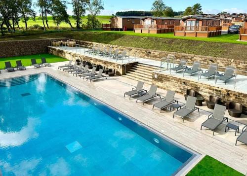 a large swimming pool with chairs and a table at Wild Rose Holiday Park in Colby