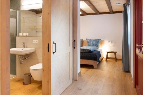 a bathroom with a sink and a toilet and a bed at Landluft Ferien - Wohnung Morgentau in Heiligenberg
