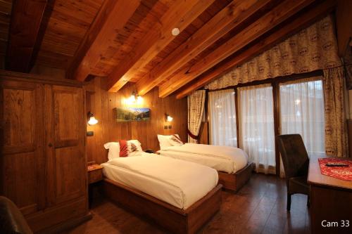 a bedroom with two beds in a room with wooden walls at Hotel Meynet in Breuil-Cervinia