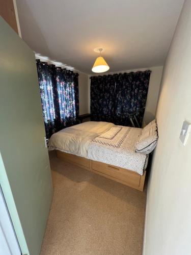 1 dormitorio pequeño con cama y cortinas en Straffan, en Straffan
