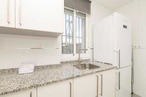 a white kitchen with a sink and a window at Castañuelas in Jerez de la Frontera