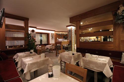 un restaurant avec des tables, des chaises et des nappes blanches dans l'établissement Hotel Meynet, à Breuil-Cervinia