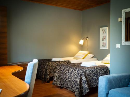 a room with two beds and a table and a chair at Poukama in Porvoo