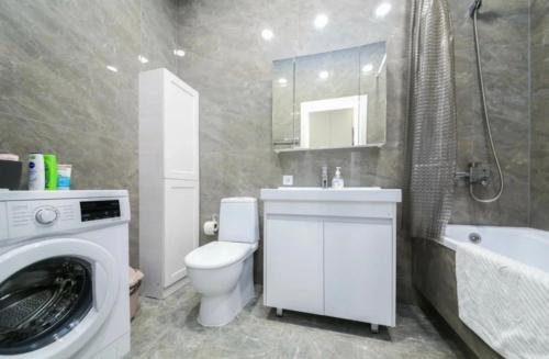 uma casa de banho com um WC e uma máquina de lavar roupa em Апартаменты жк Атлетик em Astana