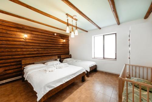 a bedroom with two beds and a wooden wall at Casa Maramureșană Beliș in Beliş