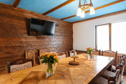 a dining room with a table and a flat screen tv at Casa Maramureșană Beliș in Beliş