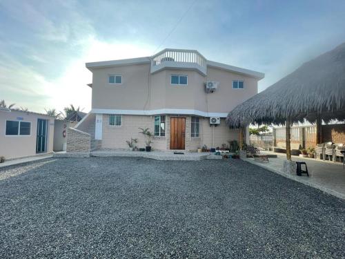 a large white house with a gravel driveway at Hostal Cabañas Vistamar in Crucita