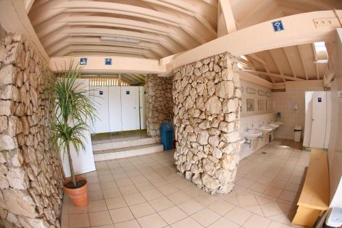 a bathroom with two sinks and a stone wall at Camping Bunculuka in Baška
