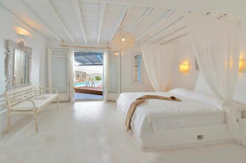 a white bedroom with a bed and a chair at Villa Princess 1 4Bed with Pool Panormos Beach in Panormos Mykonos