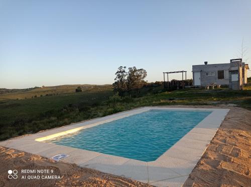 - une piscine au milieu d'un champ avec une maison dans l'établissement Carabanchel, à Canepa