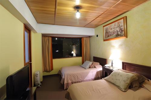 a hotel room with two beds and a television at Hotel El Puma in Cusco