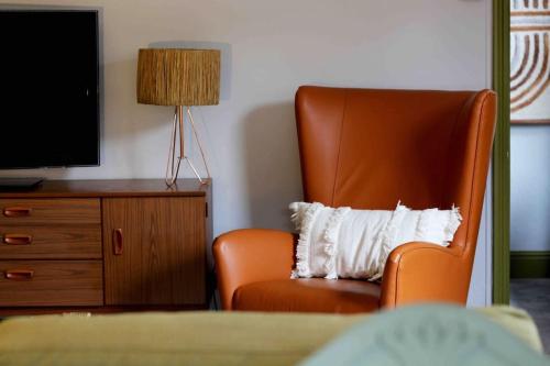 uma cadeira laranja com uma almofada num quarto de hotel em Lincoln Apartment freshly renovated common views em Lincolnshire
