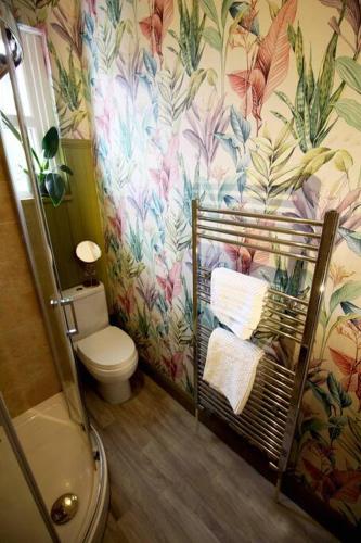 a bathroom with a toilet and a flower wallpaper at The Tree House, quiet neighbourhood in Lincolnshire