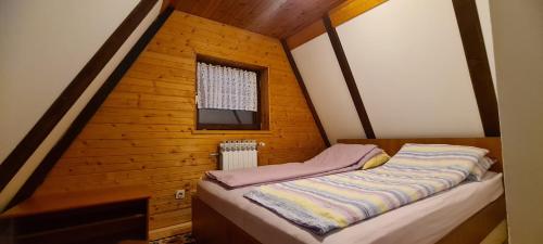 a small bed in a wooden room with a window at Vjeverica Chalet in Jahorina