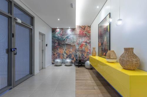 a hallway with vases on a yellow counter and a painting at Setin Downtown Praca da Sé by Viva - Prédio completo com piscina perto de estação de metrô no Centro de São Paulo in Sao Paulo