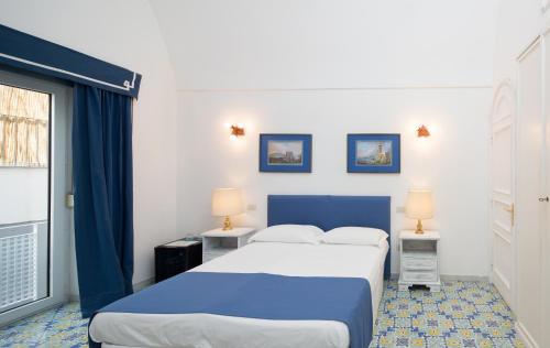 a bedroom with a blue and white bed and a window at Marlin Guest House in Capri