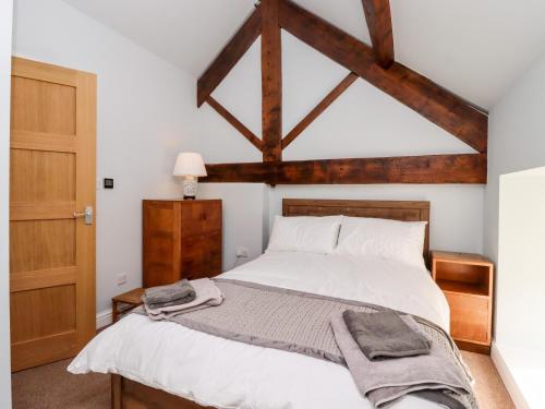 a bedroom with a large white bed with wooden beams at The Stables in Colne