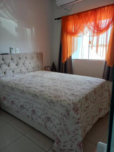 a bedroom with a bed with a flowered blanket and a window at Lar do Sossego in Araquari