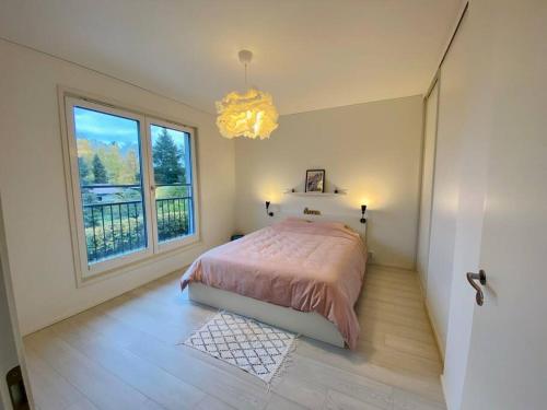 a bedroom with a bed and a window and a chandelier at Lakeside Modern Minimalist Apartment FreeParking in Järvenpää