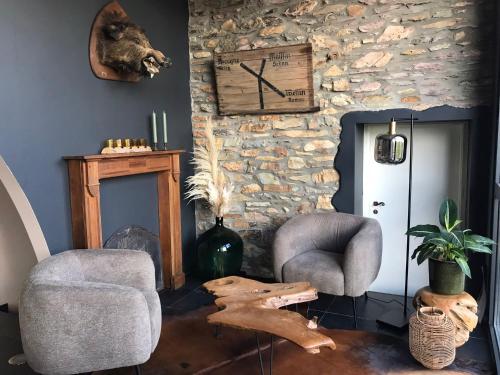 a living room with two chairs and a stone wall at Ma Bauge in Libin