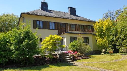 シュムペルクにあるPenzion Villa Ancoraの木々と庭のある大きな黄色の家