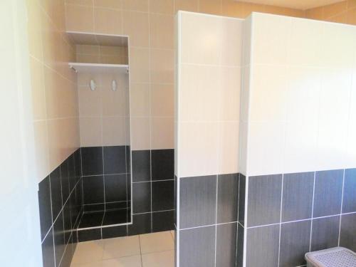 uma casa de banho com um chuveiro com azulejos pretos e brancos em Deze bis em Herm