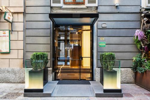 an entrance to a building with two potted plants at The Street Milano Duomo | a Design Boutique Hotel in Milan